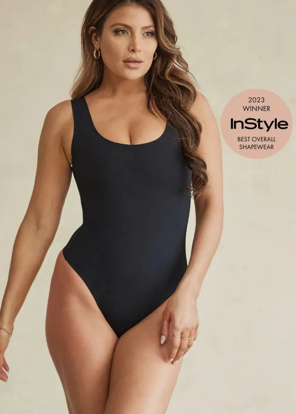 Person wearing a maroon, one-shoulder bodysuit with hands on hips.