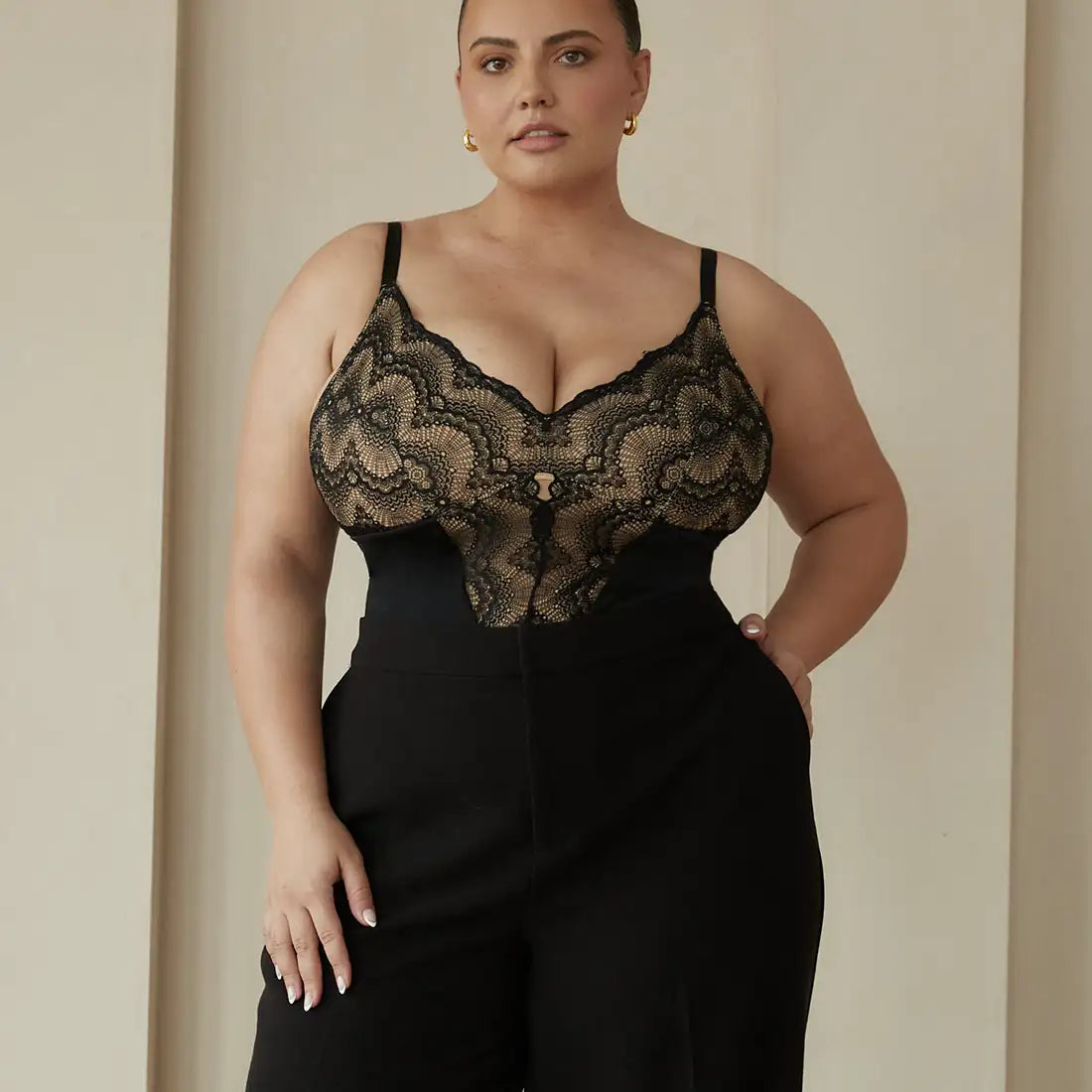 A person wearing a black lace top and high-waisted black pants.